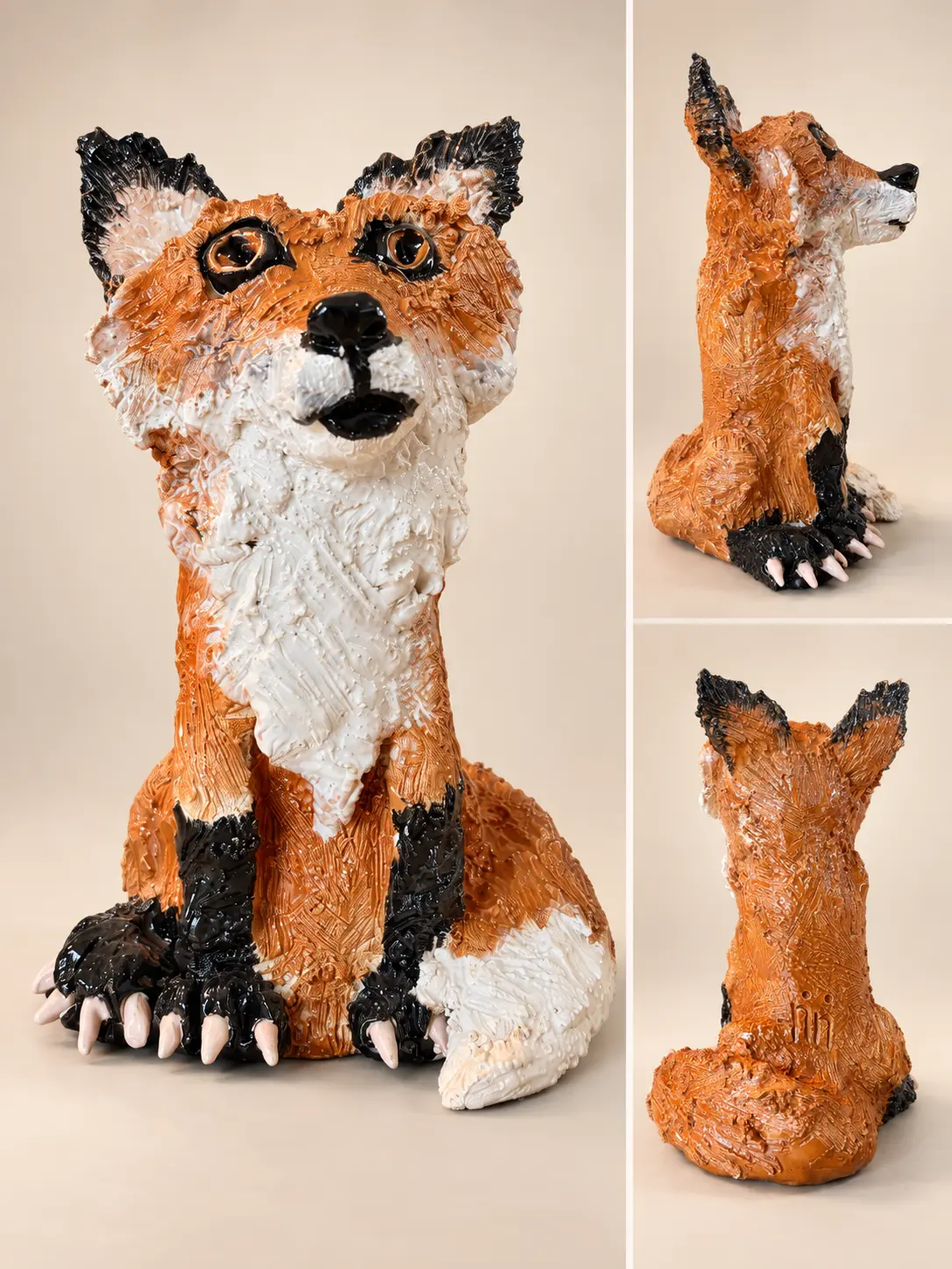 Renard assis en céramique orange, blanche et noire.